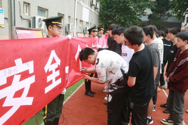 6月3日上午，高级技校在操场举办2024“安全生产月”启动仪式。图为学生在“人人讲安全、个个会应急——畅通生命通道”的主题横幅上承诺签名。（摄影：吴一楠）_副本.jpg